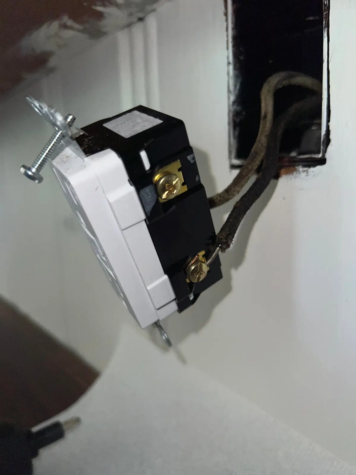 Old receptacle pulled from the wall with brittle cloth-covered wiring attached